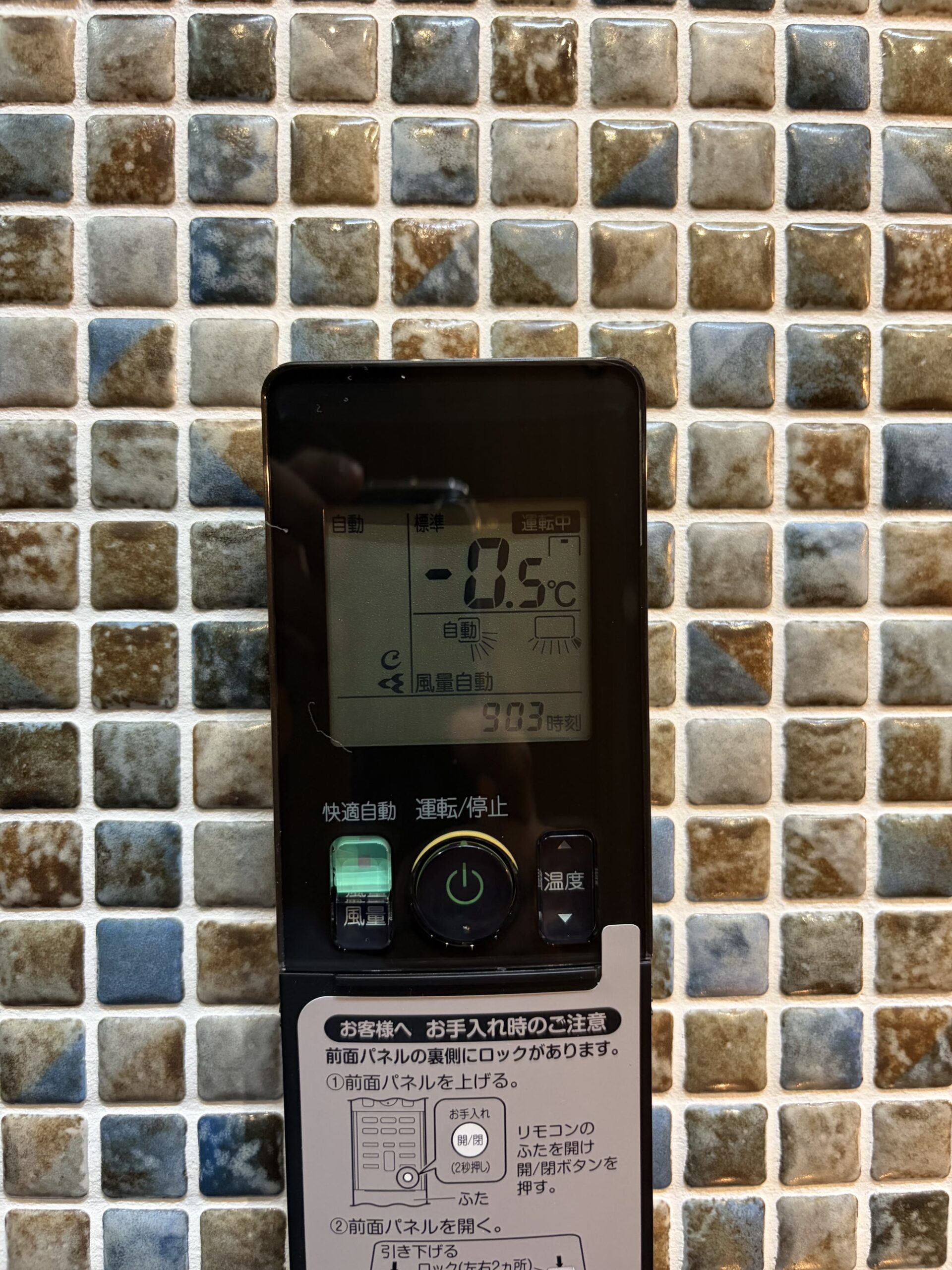 エアコンのリモコン。快適自動を標準より0.5度低い設定にして運転中と表示されている